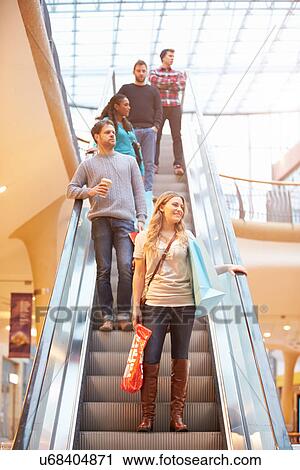 Stock Image - Female Shopper On Escalator In Shopping Mall. Fotosearch
