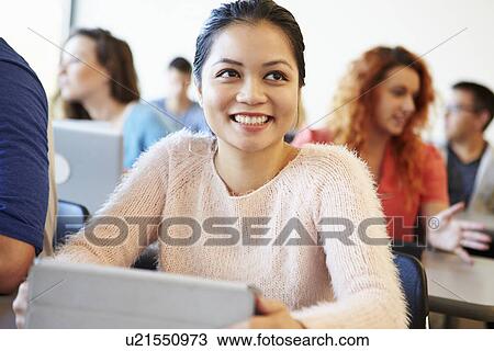 Stock Image - Female University Student Using Digital Tablet In Classroom. Fotosearch