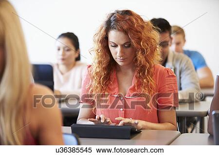 Stock Photography - Female University Student Using Digital Tablet In Classroom. Fotosearch