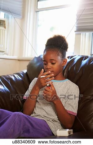 Stock Photo - Girl Discovering Parent's Pack Of Cigarettes At Home. Fotosearch