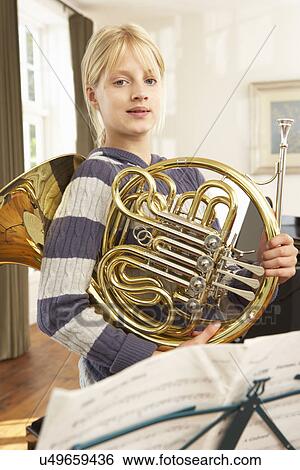 Stock Photograph - Girl holding French horn at home. Fotosearch