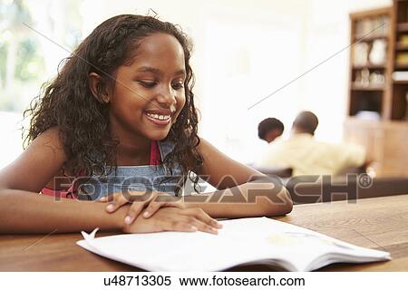 Stock Photography - Girl Reading Book For Homework At Table. Fotosearch