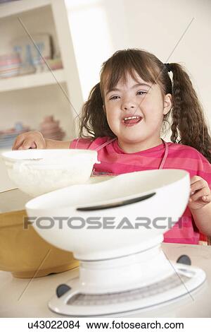 Picture - Girl with Downs Syndrome baking. Fotosearch