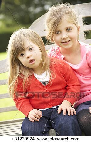 Picture - Girl with younger Downs Syndrome sister. Fotosearch