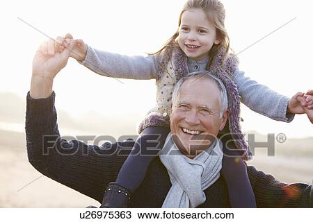 Stock Image - Grandfather And Granddaughter Walking On Winter Beach. Fotosearch