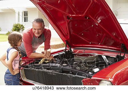 Stock Image - Grandfather And Granddaughter Work On Restored Classic Car. Fotosearch
