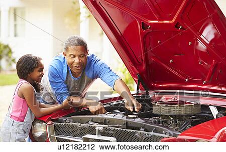Stock Image - Grandfather And Granddaughter Working On Restored Car. Fotosearch