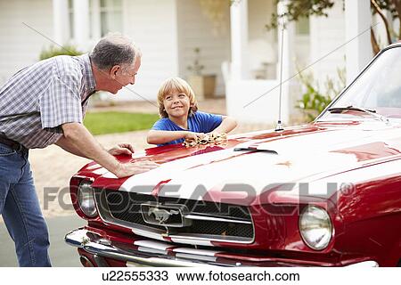 Stock Image - Grandfather And Grandson Cleaning Restored Classic Car. Fotosearch
