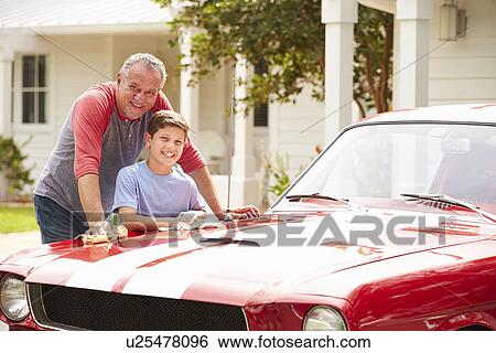 Stock Photograph - Grandfather And Grandson Cleaning Restored Classic Car. Fotosearch