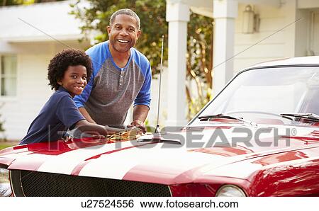 Stock Photograph - Grandfather And Grandson Cleaning Restored Classic Car. Fotosearch