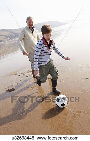 Stock Photo - Grandfather And Grandson Playing Football On Winter Beach. Fotosearch