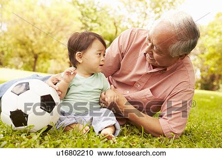 Stock Image - Grandfather And Grandson Playing With Football In Park. Fotosearch