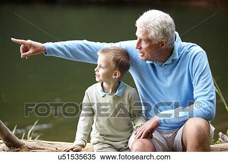 Stock Photography - Grandfather and grandson sitting by lake. Fotosearch