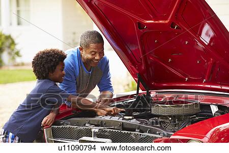 Picture - Grandfather And Grandson Working On Restored Classic Car. Fotosearch