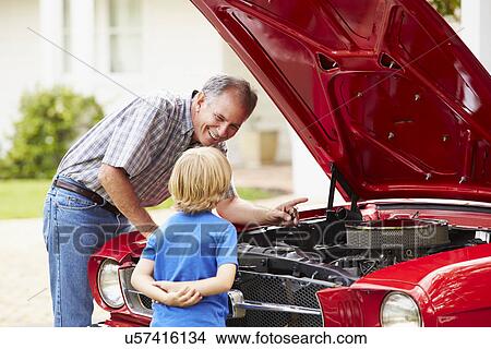Picture - Grandfather And Grandson Working On Restored Classic Car. Fotosearch
