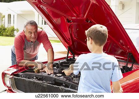 Stock Image - Grandfather And Grandson Working On Restored Classic Car. Fotosearch