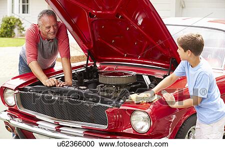 Stock Image - Grandfather And Grandson Working On Restored Classic Car. Fotosearch