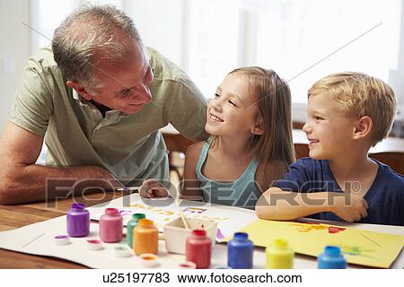 Stock Image - Grandfather Painting Picture With Grandchildren At Home. Fotosearch