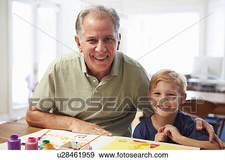 Stock Photo - Grandfather Painting Picture With Grandson At Home. Fotosearch