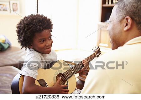 Stock Photograph - Grandfather Teaching Grandson To Play Guitar. Fotosearch