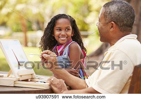 Stock Image - Grandfather With Granddaughter Outdoors Painting Landscape. Fotosearch