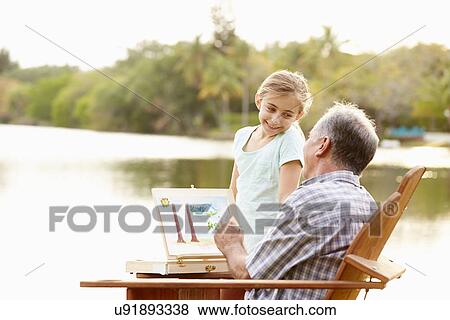 Stock Photo - Grandfather With Granddaughter Outdoors Painting Landscape. Fotosearch