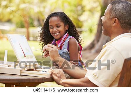 Stock Photograph - Grandfather With Granddaughter Outdoors Painting Landscape. Fotosearch