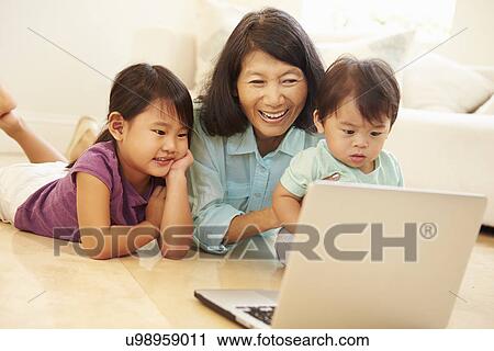 Stock Image - Grandmother And Grandchildren Using Laptop Together. Fotosearch