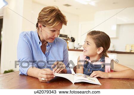 Stock Image - Grandmother Reading With Granddaughter At Home. Fotosearch