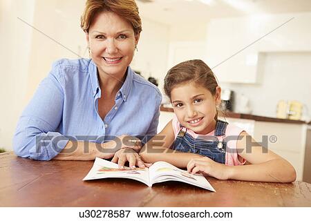 Stock Photo - Grandmother Reading With Granddaughter At Home. Fotosearch