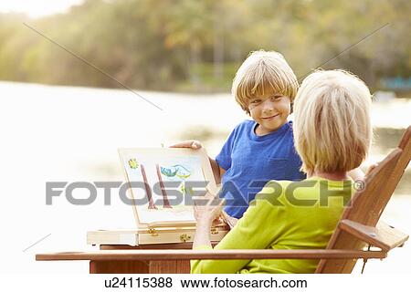 Stock Photo - Grandmother With Grandson Outdoors Painting Landscape. Fotosearch