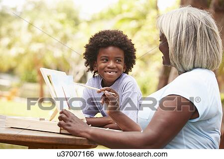 Stock Photograph - Grandmother With Grandson Outdoors Painting Landscape. Fotosearch