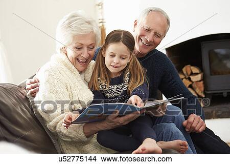 Grandparents And Granddaughter Reading Book At Home Together View Large Photo Image Picture - Grandparents And Granddaughter Reading Book At Home Together. Fotosearch