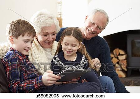 Grandparents Using Digital Tablet On Sofa With Grandchildren View Large Photo Image Stock Photography - Grandparents Using Digital Tablet On Sofa With Grandchildren. Fotosearch