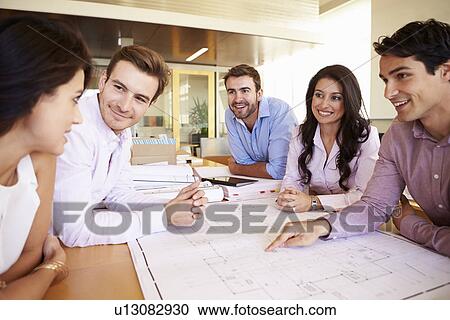 Stock Image - Group Of Architects Discussing Plans In Modern Office. Fotosearch