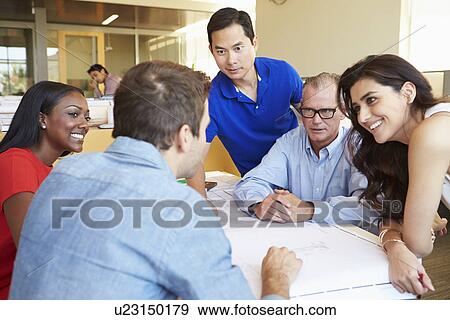 Stock Photo - Group Of Architects Discussing Plans In Modern Office. Fotosearch