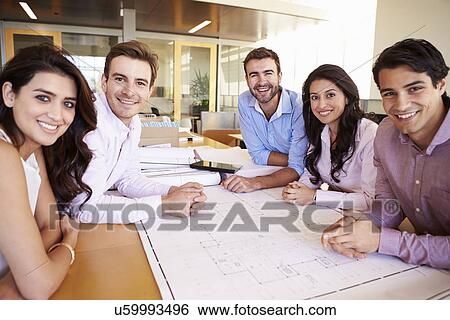 Stock Photograph - Group Of Architects Discussing Plans In Modern Office. Fotosearch