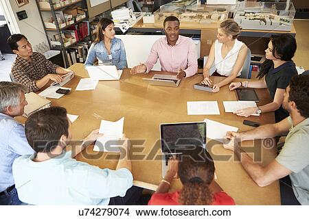 Picture - Group Of Architects Sitting Around Table Having Meeting. Fotosearch