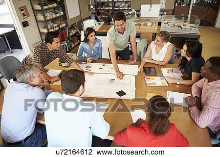 Stock Image - Group Of Architects Sitting Around Table Having Meeting. Fotosearch