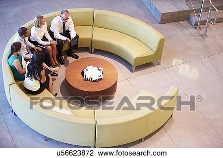 Stock Image - Group Of Businesspeople Having Meeting In Office Lobby. Fotosearch
