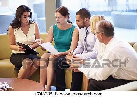 Stock Photo - Group Of Businesspeople Having Meeting In Office Lobby. Fotosearch