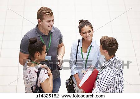 Stock Image - Group Of College Students Standing In Hallway Talking. Fotosearch