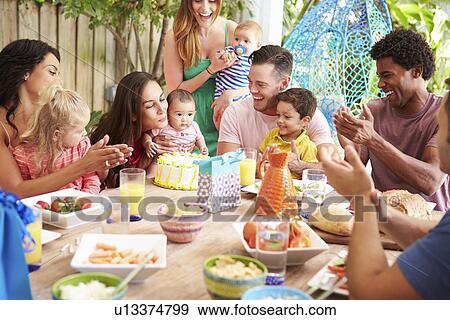 Stock Photo - Group Of Families Celebrating Child's Birthday At Home. Fotosearch