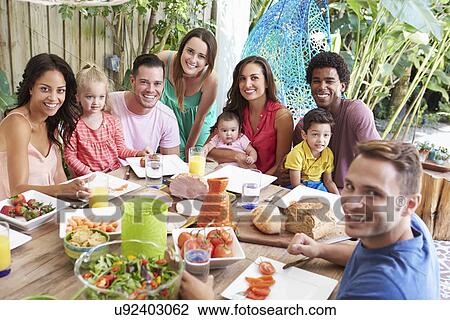 Stock Image - Group Of Families Enjoying Outdoor Meal At Home. Fotosearch