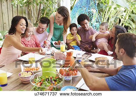 Stock Photo - Group Of Families Enjoying Outdoor Meal At Home. Fotosearch