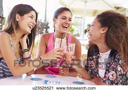 Stock Image - Group Of Female Friends Drinking Cocktails At Outdoor Bar. Fotosearch