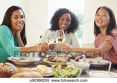 Stock Photo - Group Of Female Friends Enjoying Meal At Home. Fotosearch
