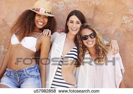Stock Photo - Group Of Female Friends On Holiday Together Posing By Wall. Fotosearch