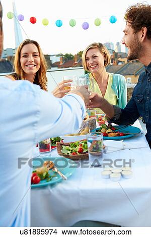 Picture - Group Of Friends Eating Meal On Rooftop Terrace. Fotosearch