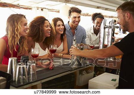 Group Of Friends Enjoying Drink At Outdoor Bar View Large Photo Image Stock Photo - Group Of Friends Enjoying Drink At Outdoor Bar. Fotosearch